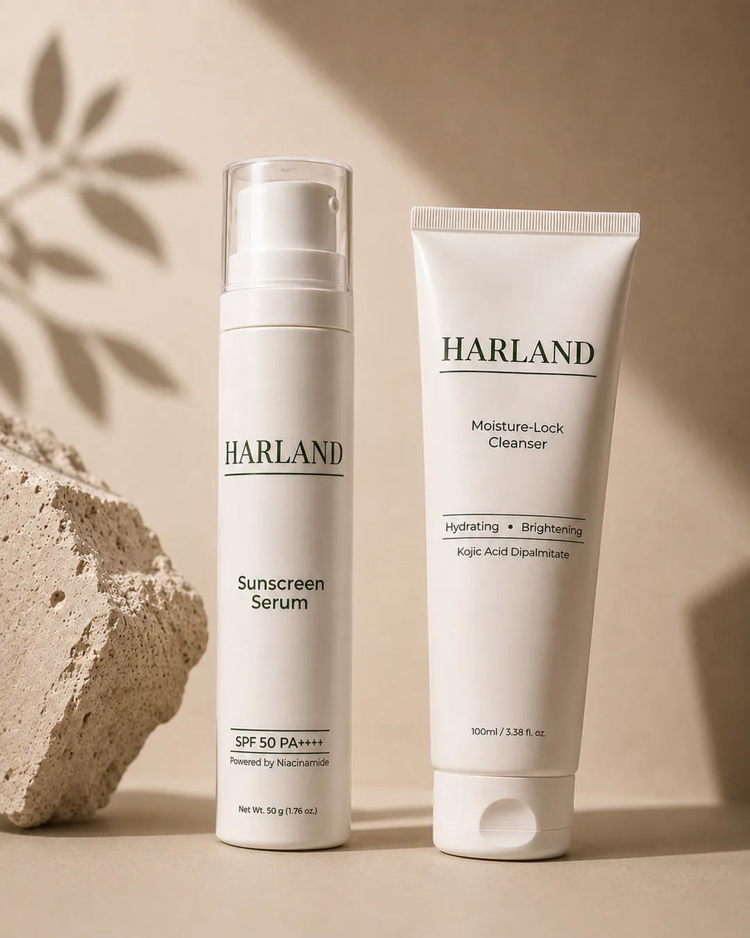 The HARLAND Face set — the Sunscreen Serum and the Moisture-Lock Cleanser standing together against travertine, leaf shadows on the wall behind.
